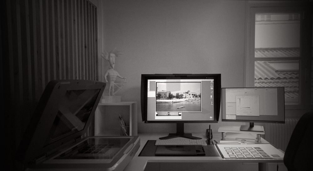 Scanner à plat ouvert à côté d’un écran affichant une photographie en cours de numérisation